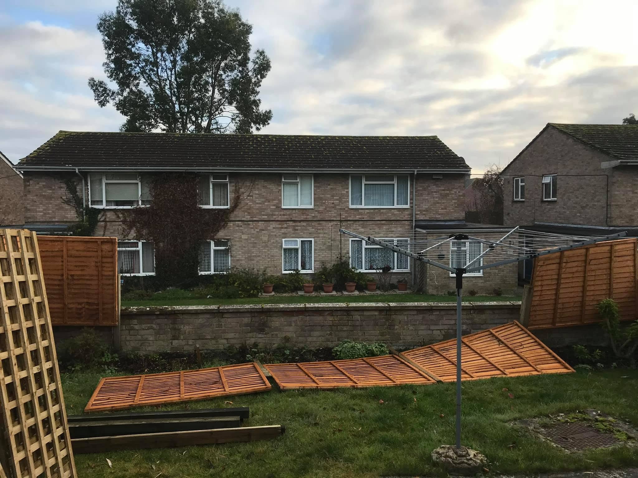 Old fence panels taken down and lying on the lawn behind a block of flats