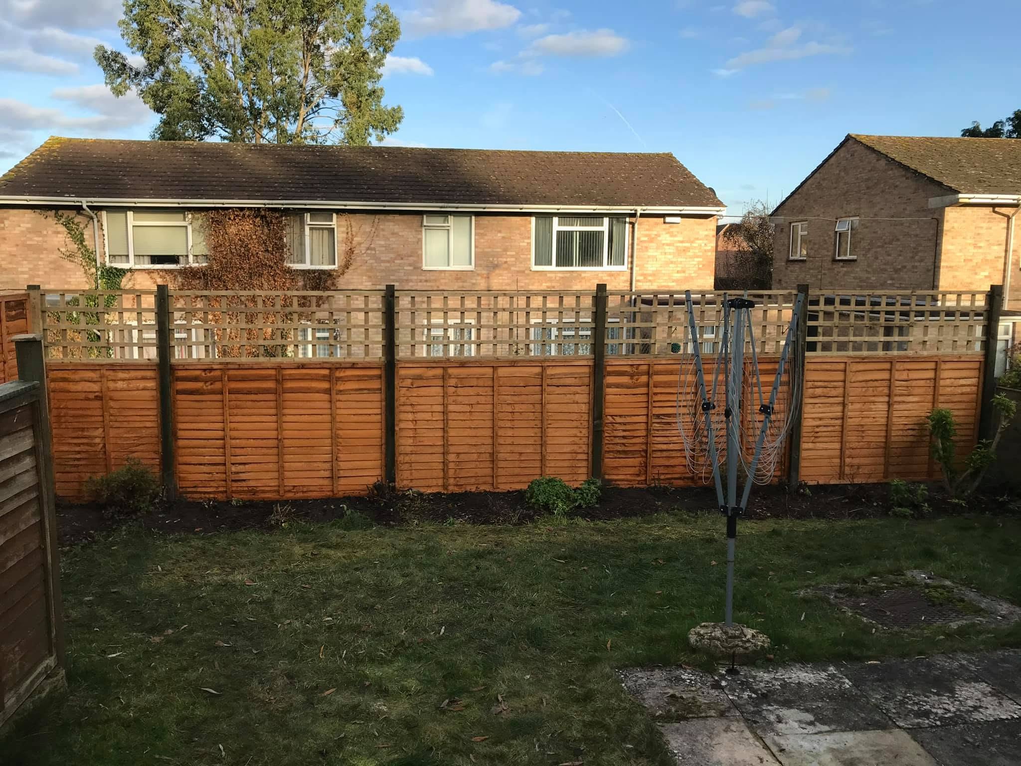 New lap fence panels with trellis tops on concrete posts along the same boundary