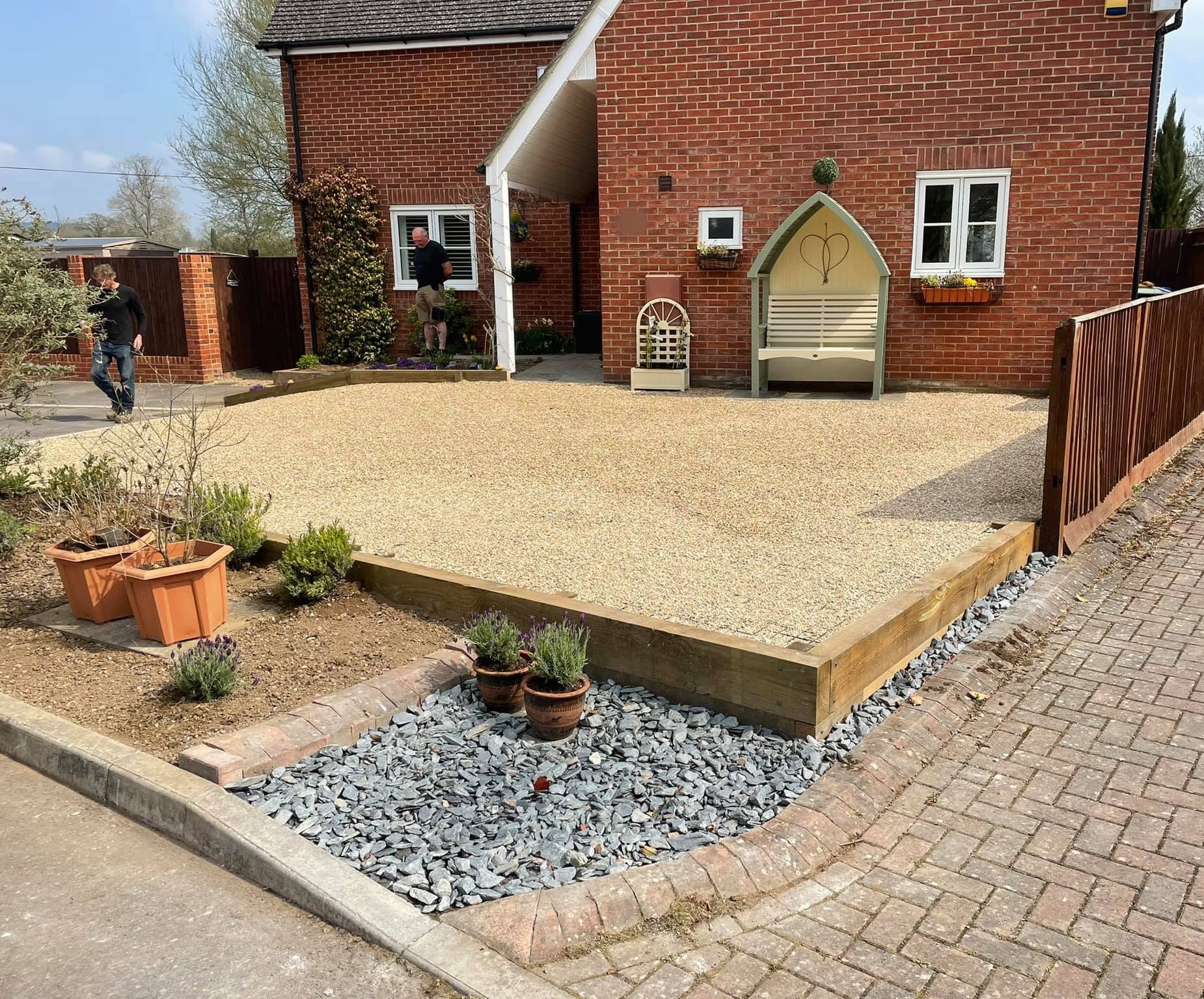 Front garden with a gravel area edged in sleepers, slate chippings and planters