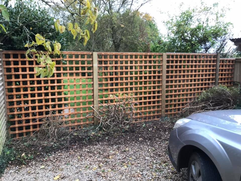 Square trellis fence panels along a gravel drive
